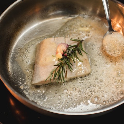Inn & Restaurant in Parsberg serving regional cuisine Fish fillet with garlic and rosemary frying in butter in a pan