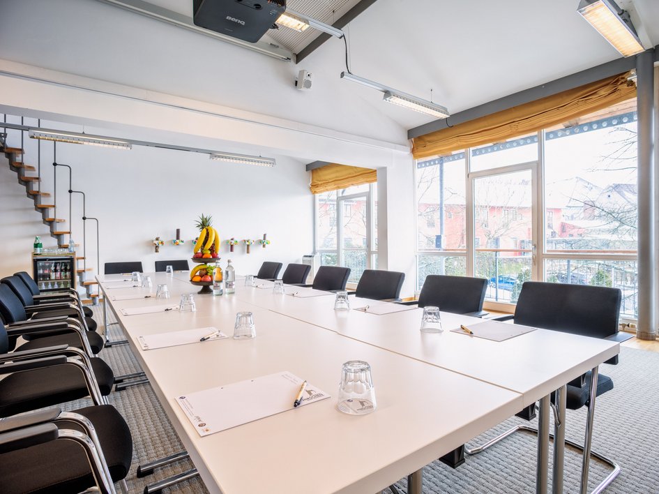 Services and rates for conferences and celebrations Bright modern meeting room with tables, chairs, and a fruit basket