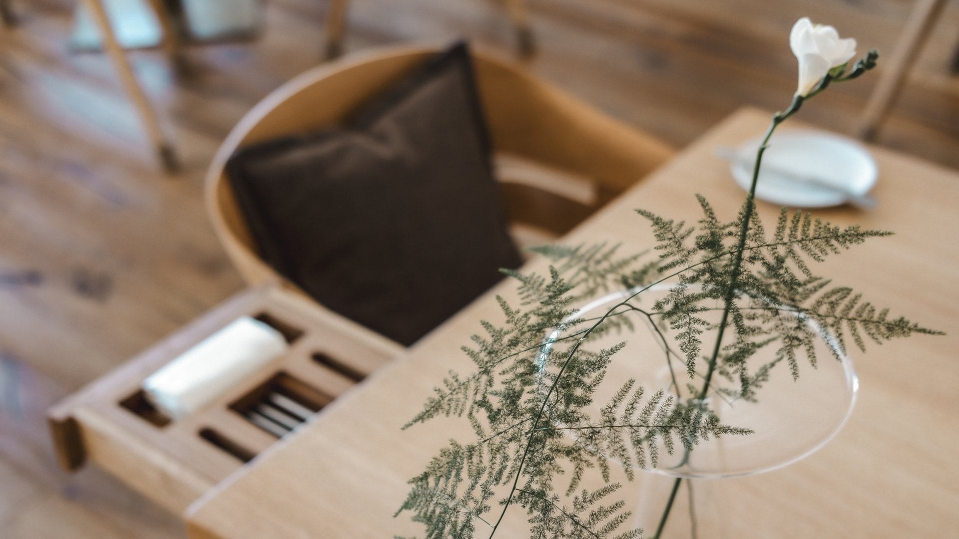 Fine Dining & Gourmet Cuisine in the Upper Palatinate White flower and fern in glass vase on wooden table beside chair with brown cushion