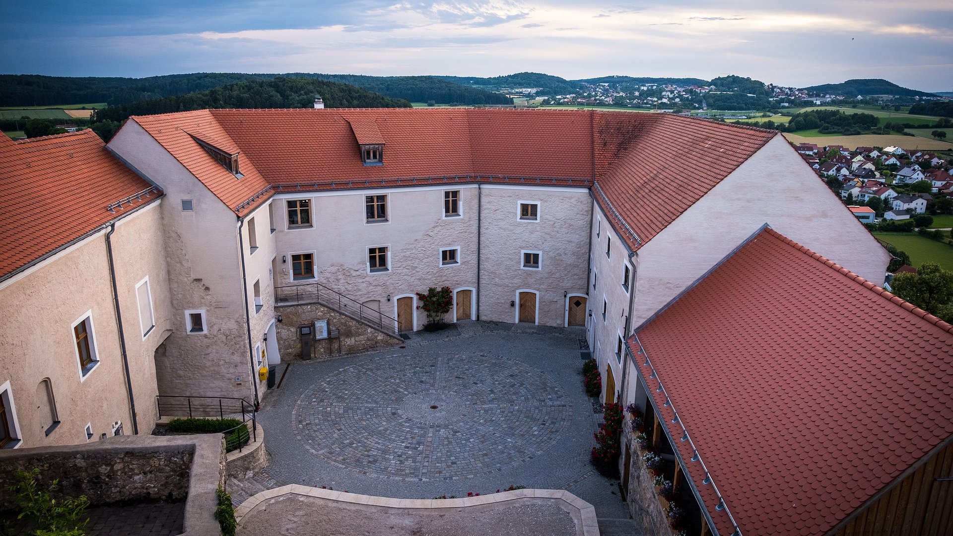 Hotels in Regensburg and its surroundings: culturally rich! Courtyard of a historic building with red tile roofs and surrounding landscape view