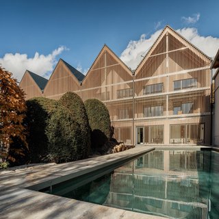 Beer garden love Modern building with wooden facade and pool in front under clear blue sky