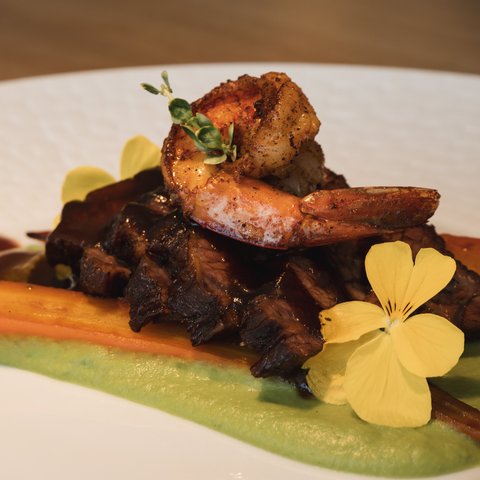 Restaurant in Parsberg: Enjoy gourmet Shrimp on meat with carrot, green sauce, and edible flowers.