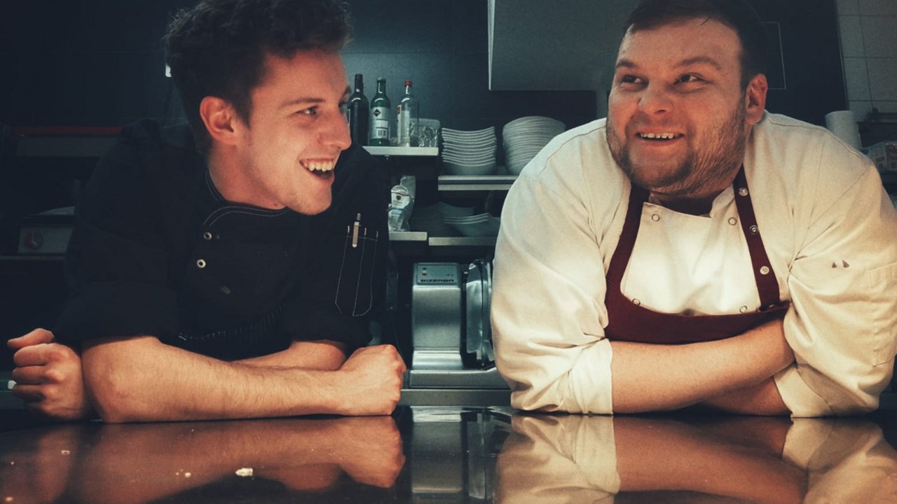 Everyone’s favourite Two chefs leaning and laughing on a kitchen countertop
