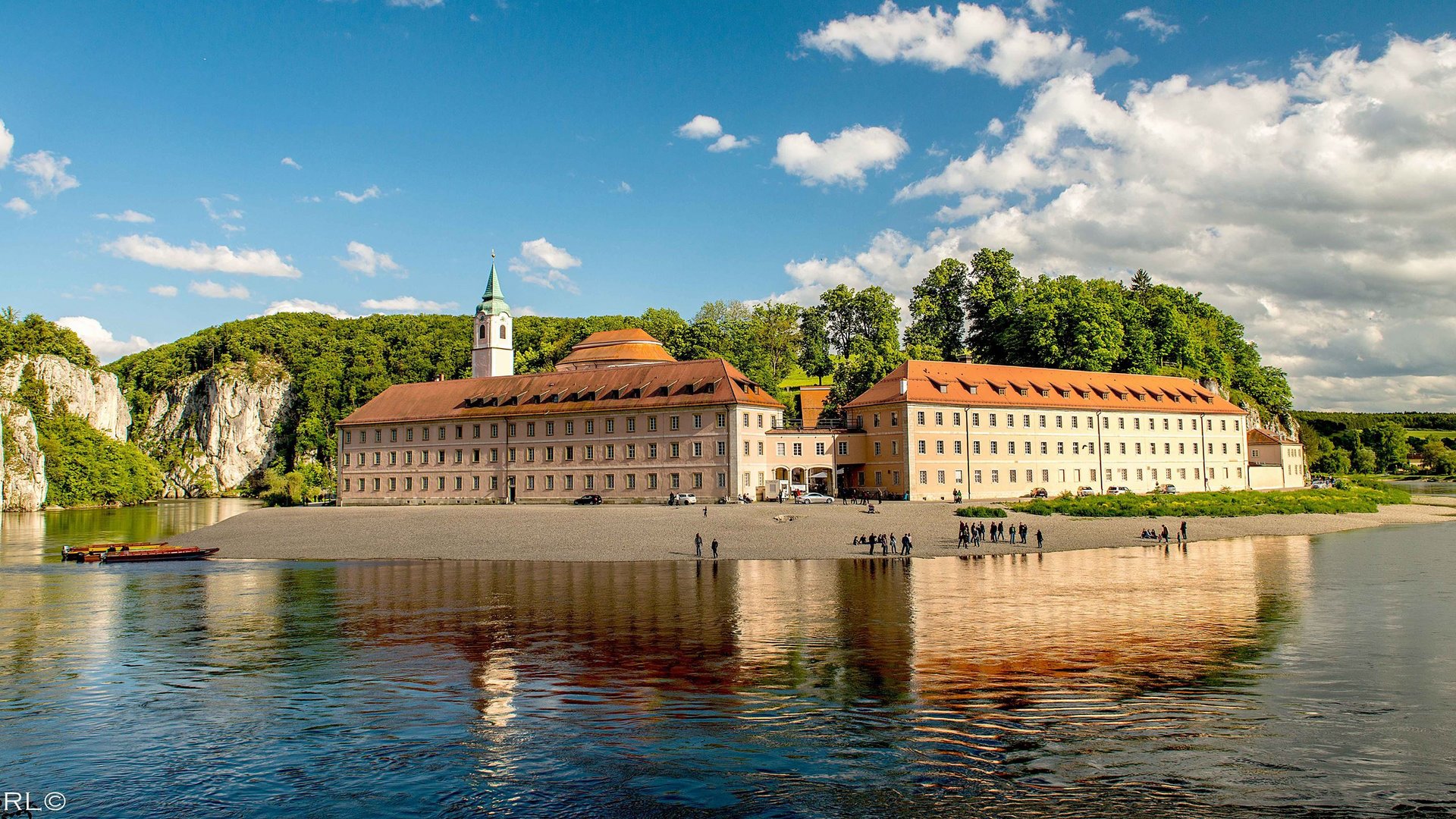 Hotels in Regensburg and its surroundings: culturally rich! Monastery on Danube shore with fishing boats and forested cliffs in background