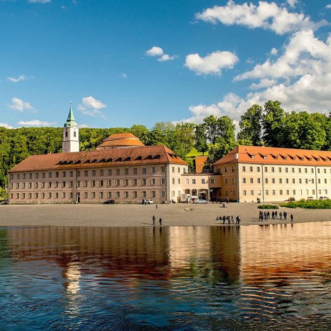 Hotels in Regensburg and its surroundings: culturally rich! Monastery on Danube shore with fishing boats and forested cliffs in background