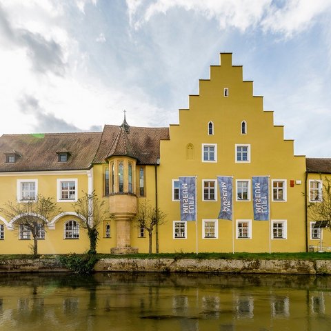 Hotels in Regensburg and its surroundings: culturally rich! Yellow historic building by water with stepped gable and flags