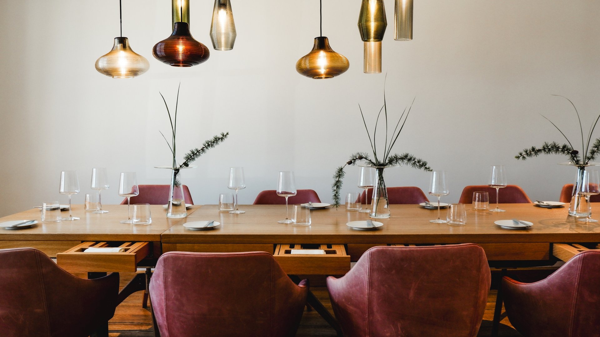 Restaurant in Parsberg: Enjoy gourmet Modern dining table with red chairs and hanging pendant lights