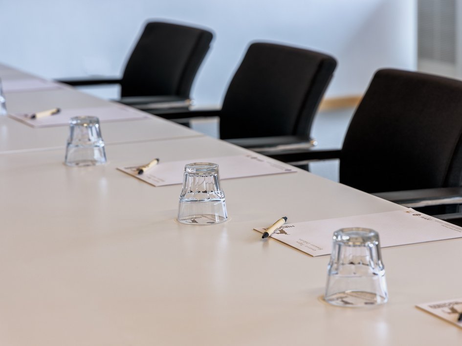 Services and rates for conferences and celebrations Conference table with chairs, glasses, notepads, and pens arranged