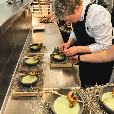 Restaurant in Parsberg: Enjoy gourmet Chef preparing soup with shrimp and green garnish in a professional kitchen