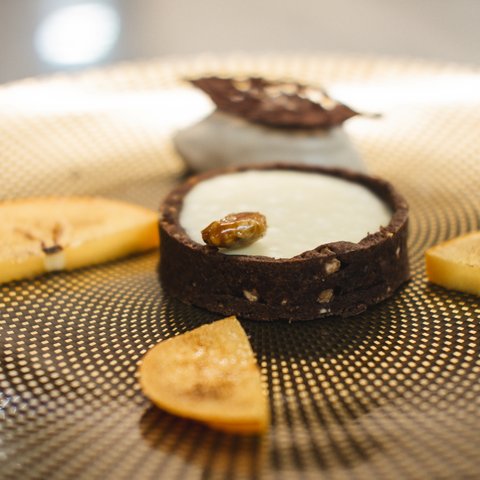 Restaurant in Parsberg: Enjoy gourmet Chocolate tart with white cream and caramelized banana slices on patterned plate