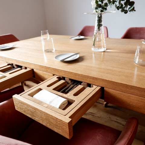 Restaurant in Parsberg: Enjoy gourmet Wooden table with pull-out cutlery drawer and elegantly set dining area
