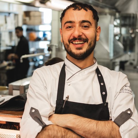 Gasthof & Restaurant in Parsberg mit regionaler Küche Lächelnder Koch mit weißer Uniform und schwarzer Schürze in professioneller Küche