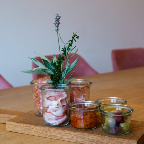 Gasthof & Restaurant in Parsberg mit regionaler Küche Holzbrett mit Glasgefäßen gefüllt mit Wurst, Kräutern, Oliven und Dips