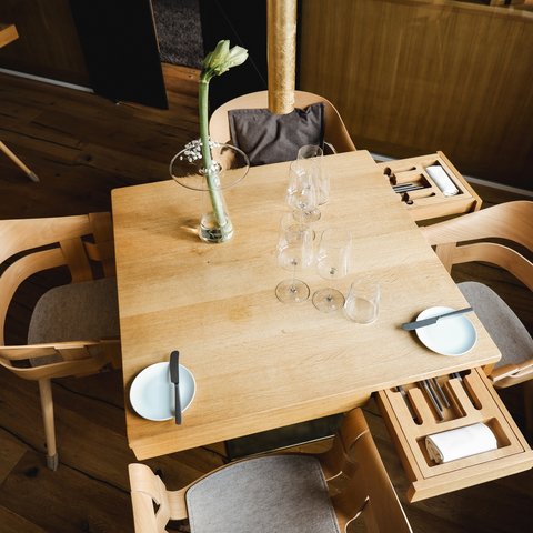 Restaurant in Parsberg: Enjoy gourmet Wooden table with four chairs, glasses, plates, and a flower in a vase
