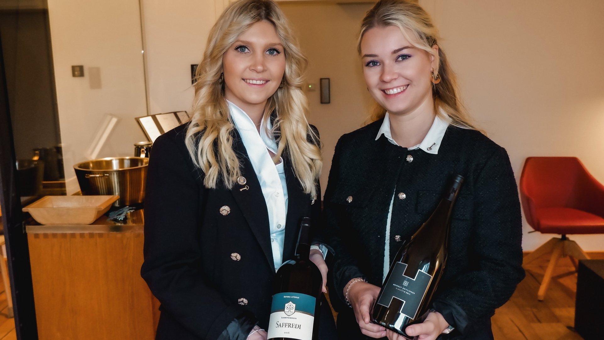 Restaurant in Parsberg: Enjoy gourmet Two women holding wine bottles in a modern indoor setting