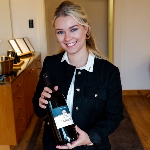 Gasthof & Restaurant in Parsberg mit regionaler Küche Frau hält eine Flasche Saffredi Rotwein lächelnd in Innenraum