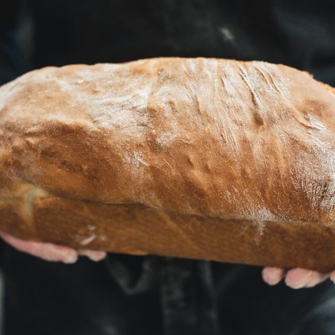 Gasthof & Restaurant in Parsberg mit regionaler Küche Person hält frisches, großes Laib Brot in den Händen