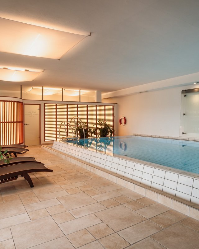 Home Hallenbad mit Liegestühlen und Pflanzen in hell beleuchtetem Raum