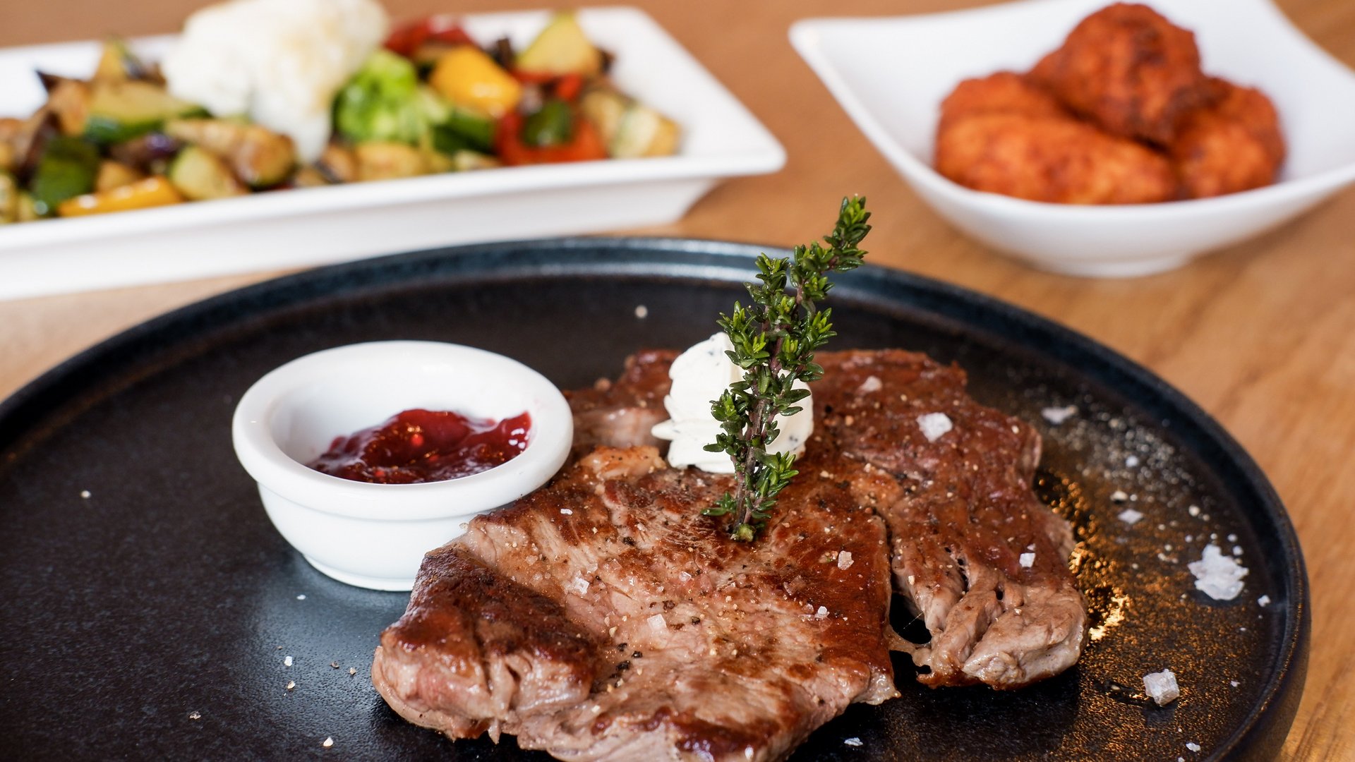 Gasthof & Restaurant in Parsberg mit regionaler Küche Gegrilltes Steak mit Kräuterbutter, Sauce und Gemüse auf Tellern