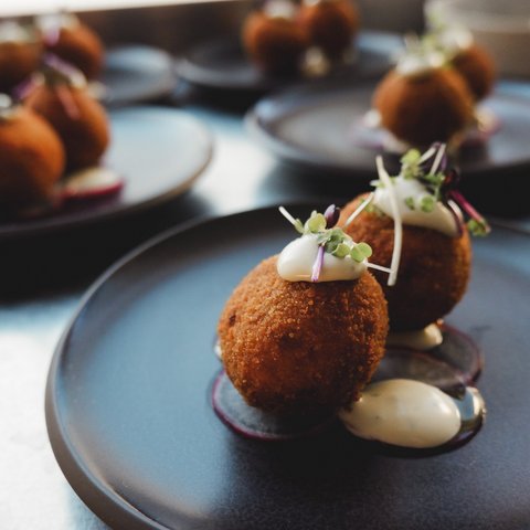 Restaurant in Parsberg: Enjoy gourmet Crispy fried appetizers with cream and microgreens on a black plate