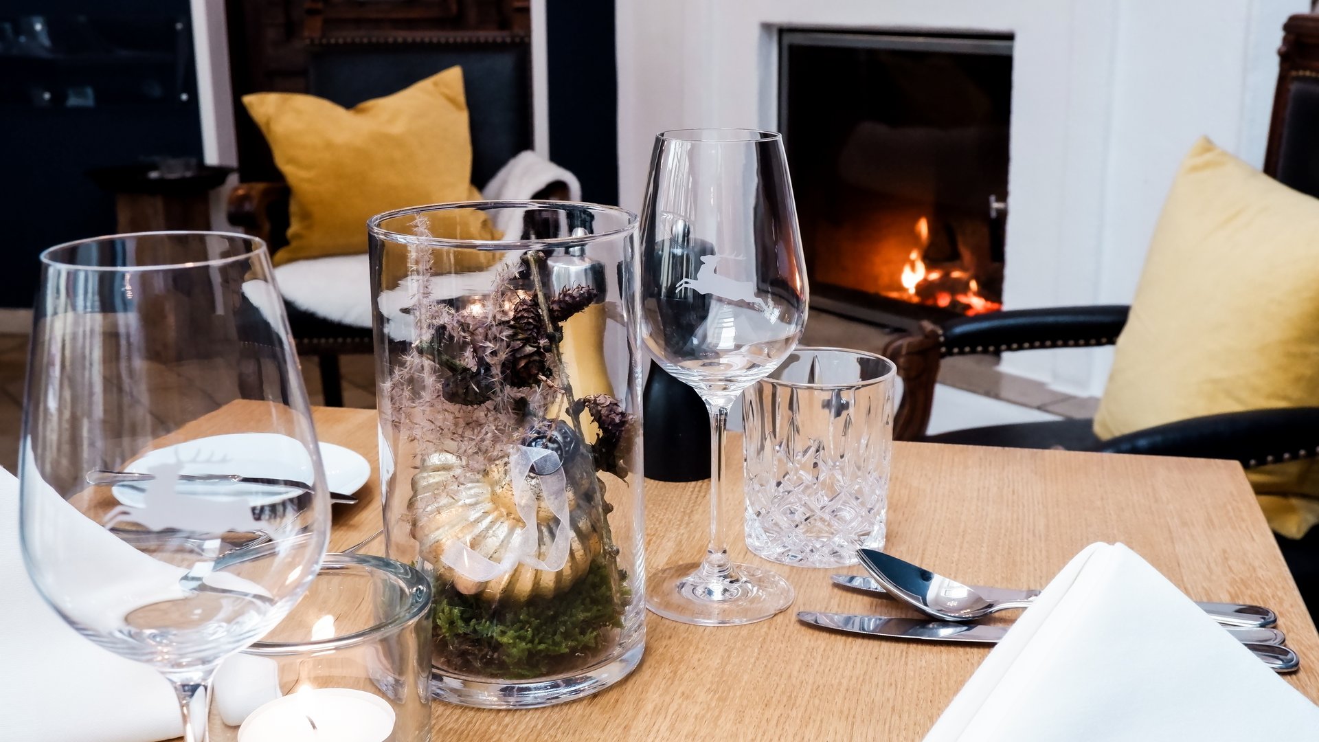 Gasthof & Restaurant in Parsberg mit regionaler Küche Gemütlich gedeckter Tisch vor Kamin mit Glasdekoration und gelben Kissen