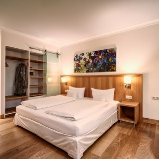 A night fit for a king Modern hotel room with double bed, wooden floor, and open wardrobe