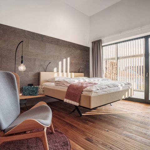 Home Modernes Schlafzimmer mit Holzfußboden, Sessel und großen Fenstern