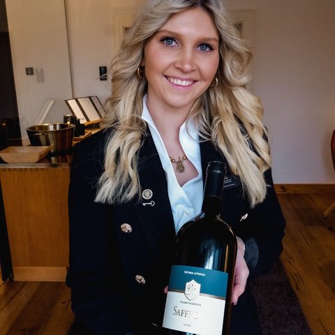 Restaurant in Parsberg: Enjoy gourmet Woman holding a bottle of 2016 Saffredi red wine smiling indoors