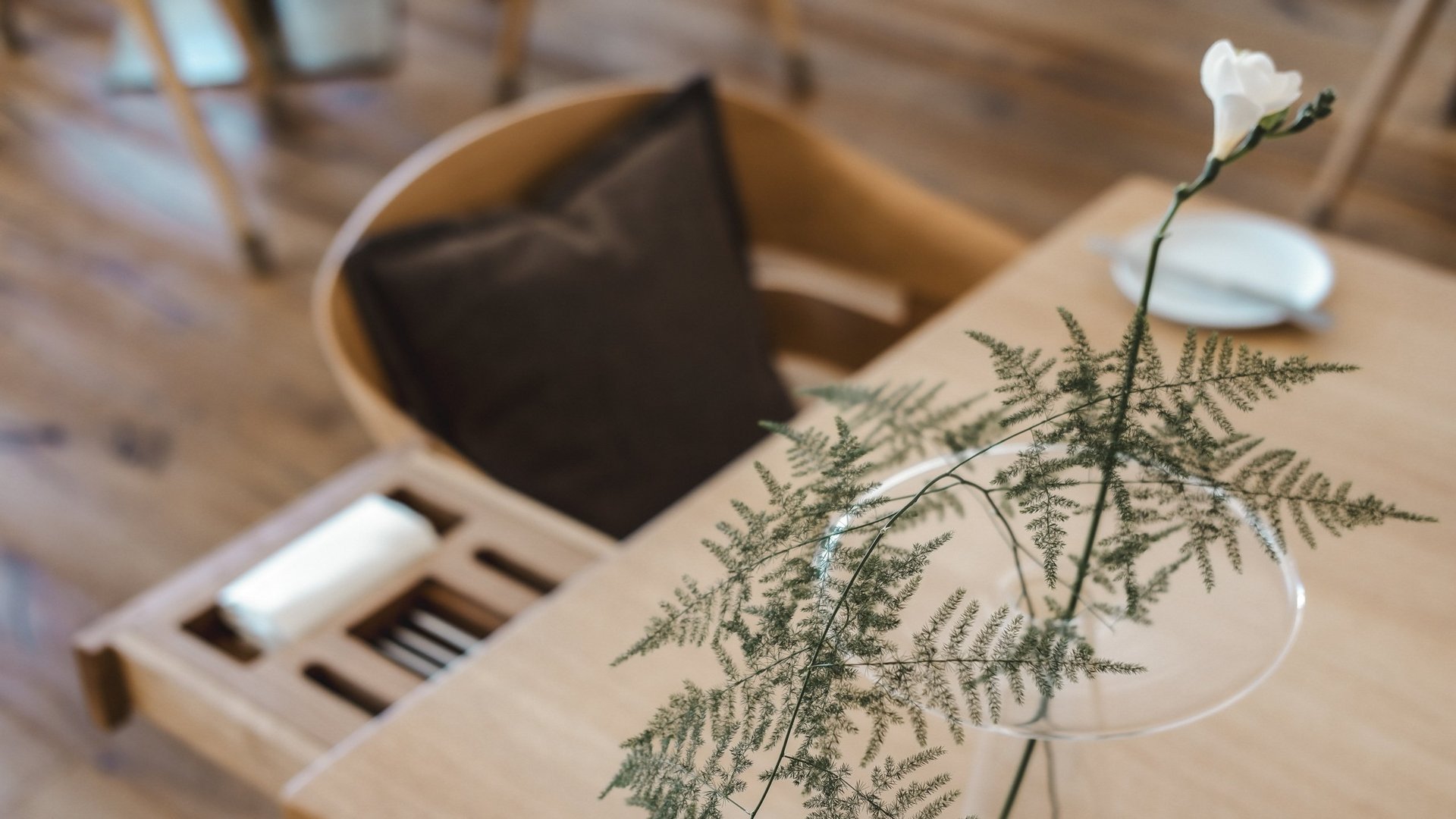 Restaurant in Parsberg: Enjoy gourmet White flower and fern in glass vase on wooden table beside chair with brown cushion