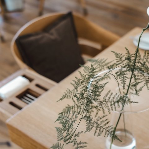 Restaurant in Parsberg: Enjoy gourmet White flower and fern in glass vase on wooden table beside chair with brown cushion