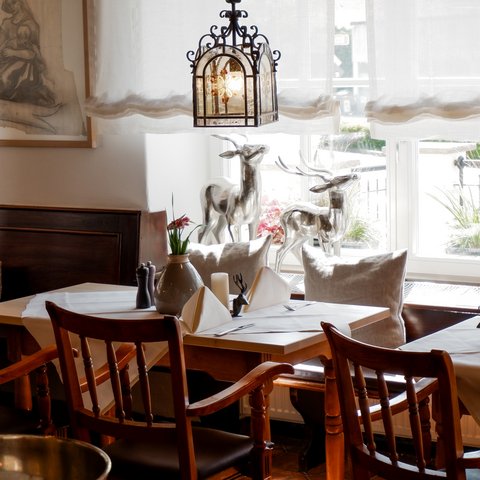 Gasthof & Restaurant in Parsberg mit regionaler Küche Gemütliches Restaurant mit Holzstühlen, Tischdekoration und Fensterdeko mit Hirschfiguren