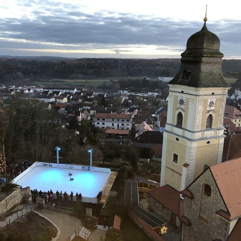 Hotels in Regensburg and its surroundings: culturally rich! Ice skating rink with lights next to historic church tower in village at dusk