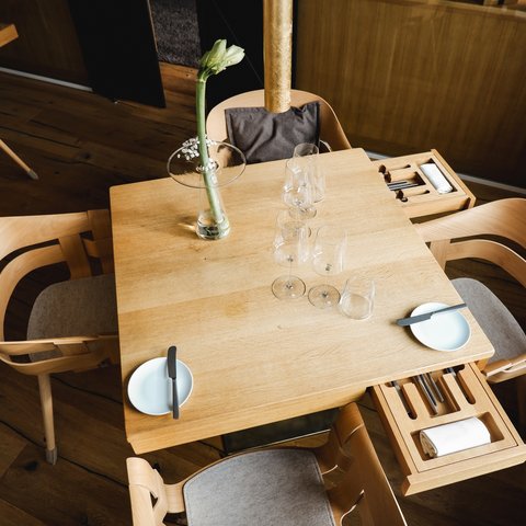 Restaurant in Parsberg: Enjoy gourmet Wooden table with four chairs, glasses, plates, and a flower in a vase