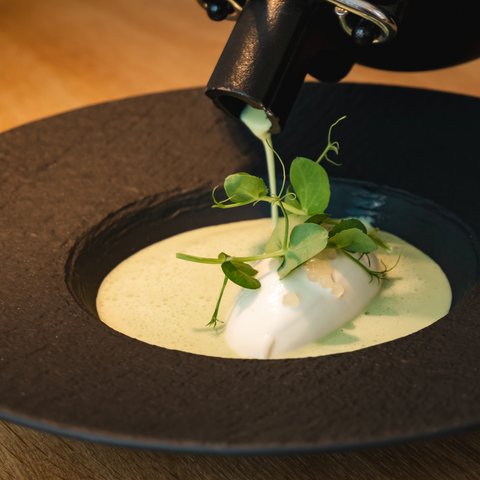 Restaurant in Parsberg: Enjoy gourmet Creamy sauce being poured over artistic plated dish with fresh herbs