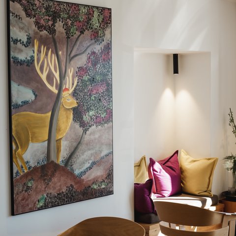 Restaurant in Parsberg: Enjoy gourmet Painting of a deer on wall next to cozy chairs with pillows in a modern seating area