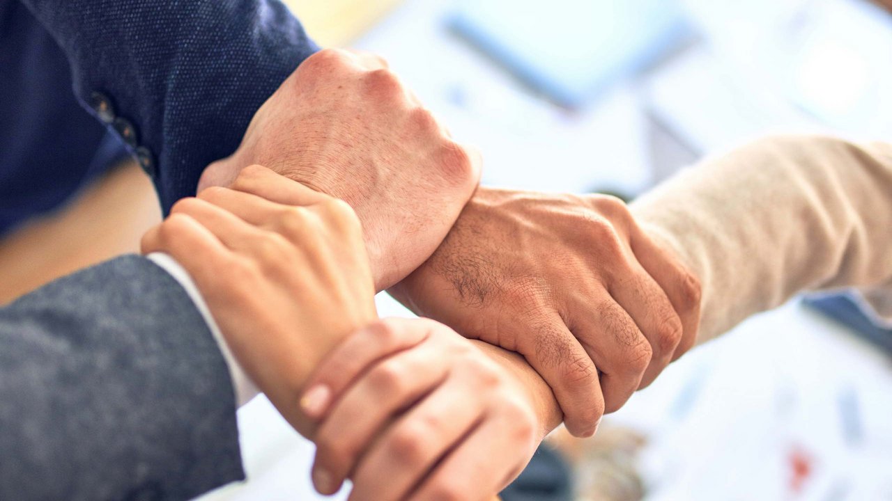 Enhancing team spirit Four hands joined together in a business meeting symbolizing teamwork